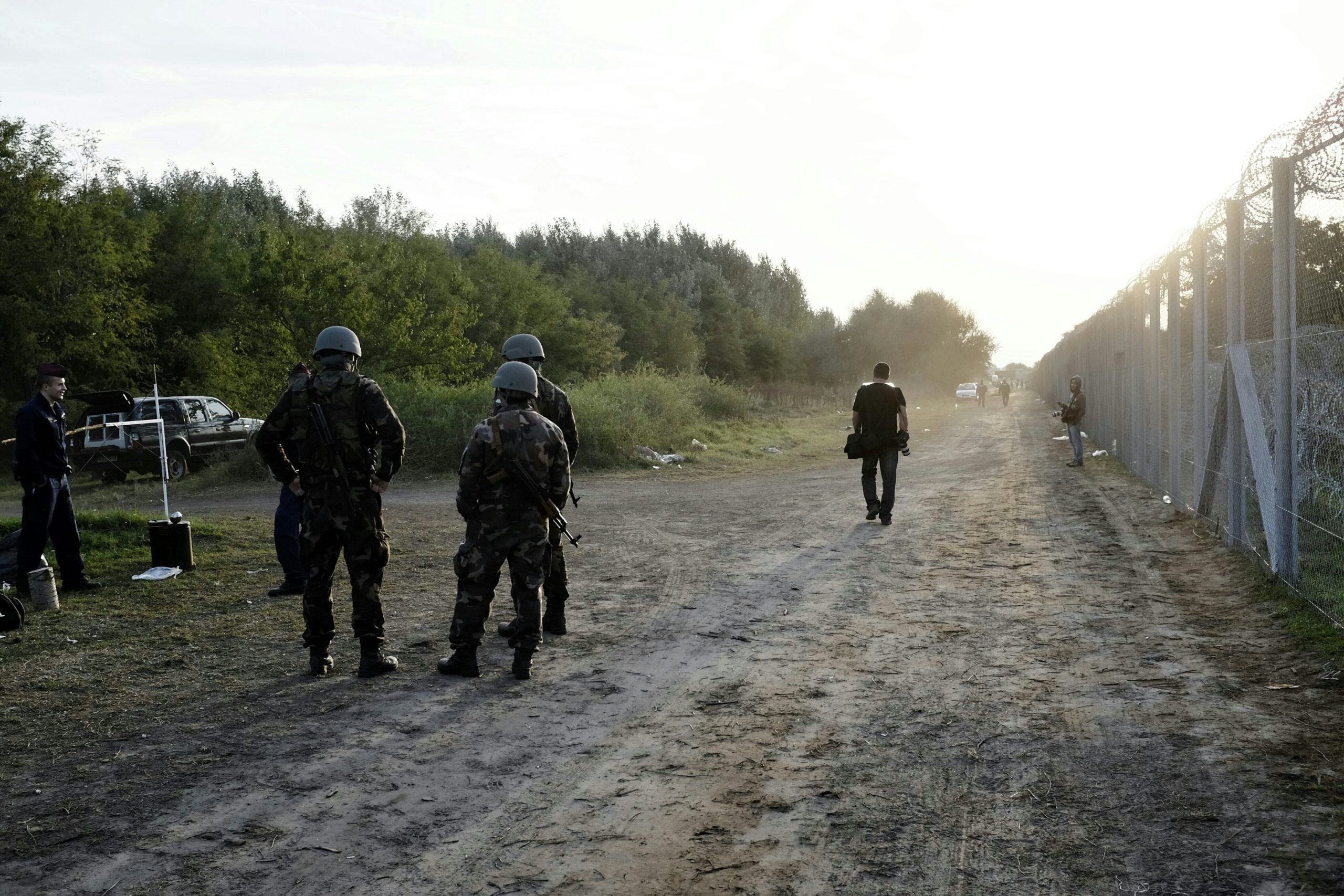 Állig felfegyverzett rendőrök gyűjtik be a migránsokat a déli határnál